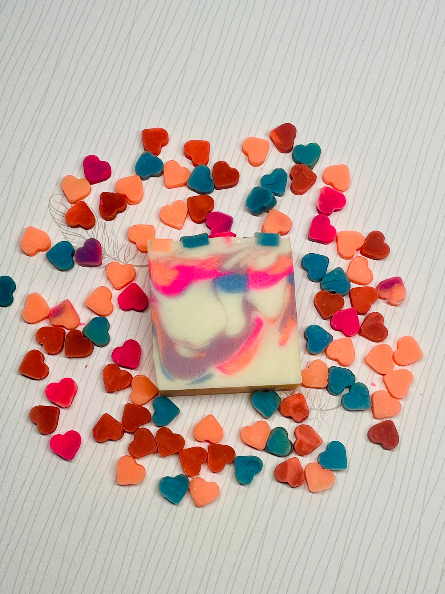 Mini colorful hearts surrounding one soap bar with colorful swirls